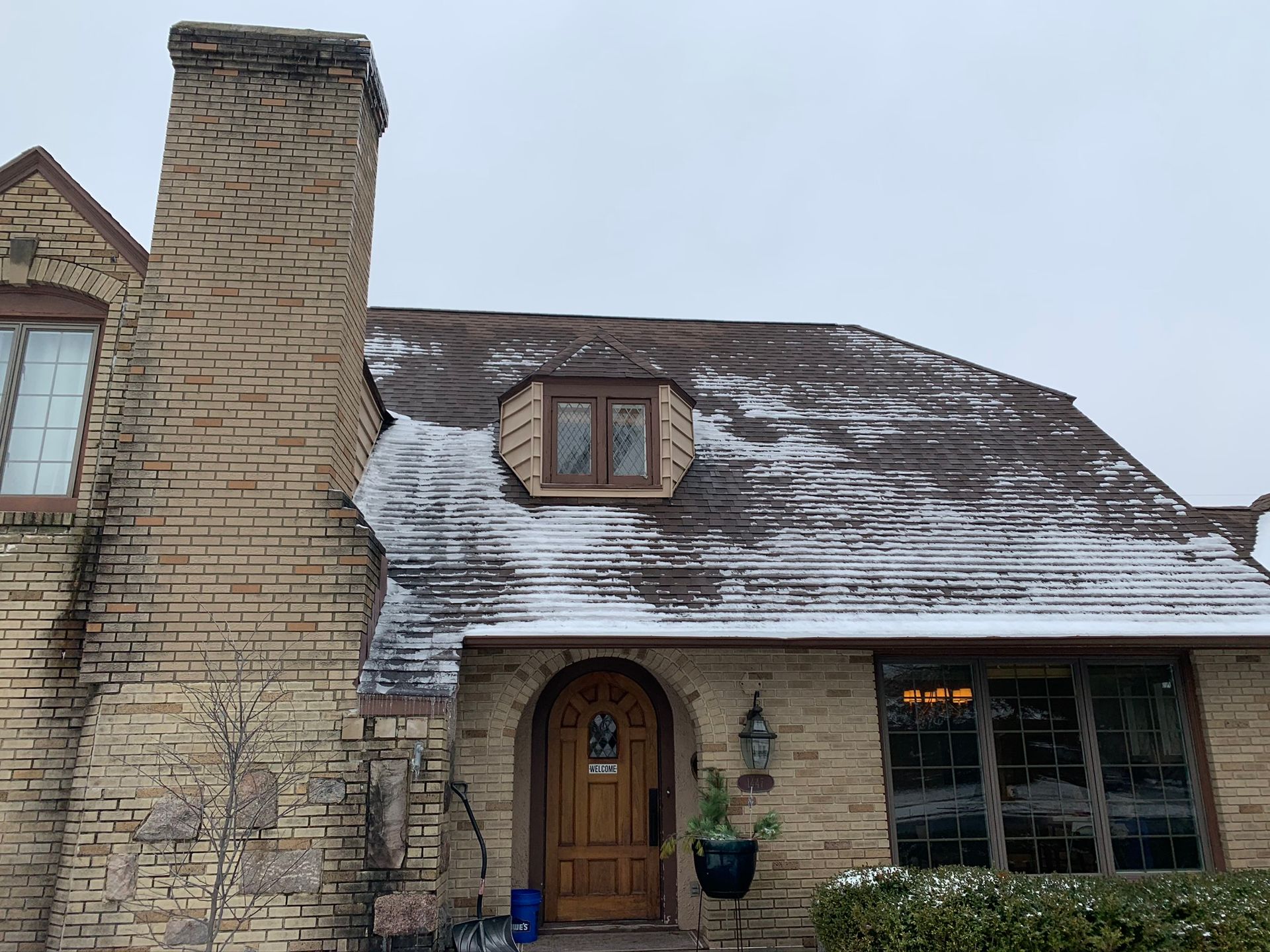 Stone cottage with a tall chimney, arched wooden door, and snow-dusted roof