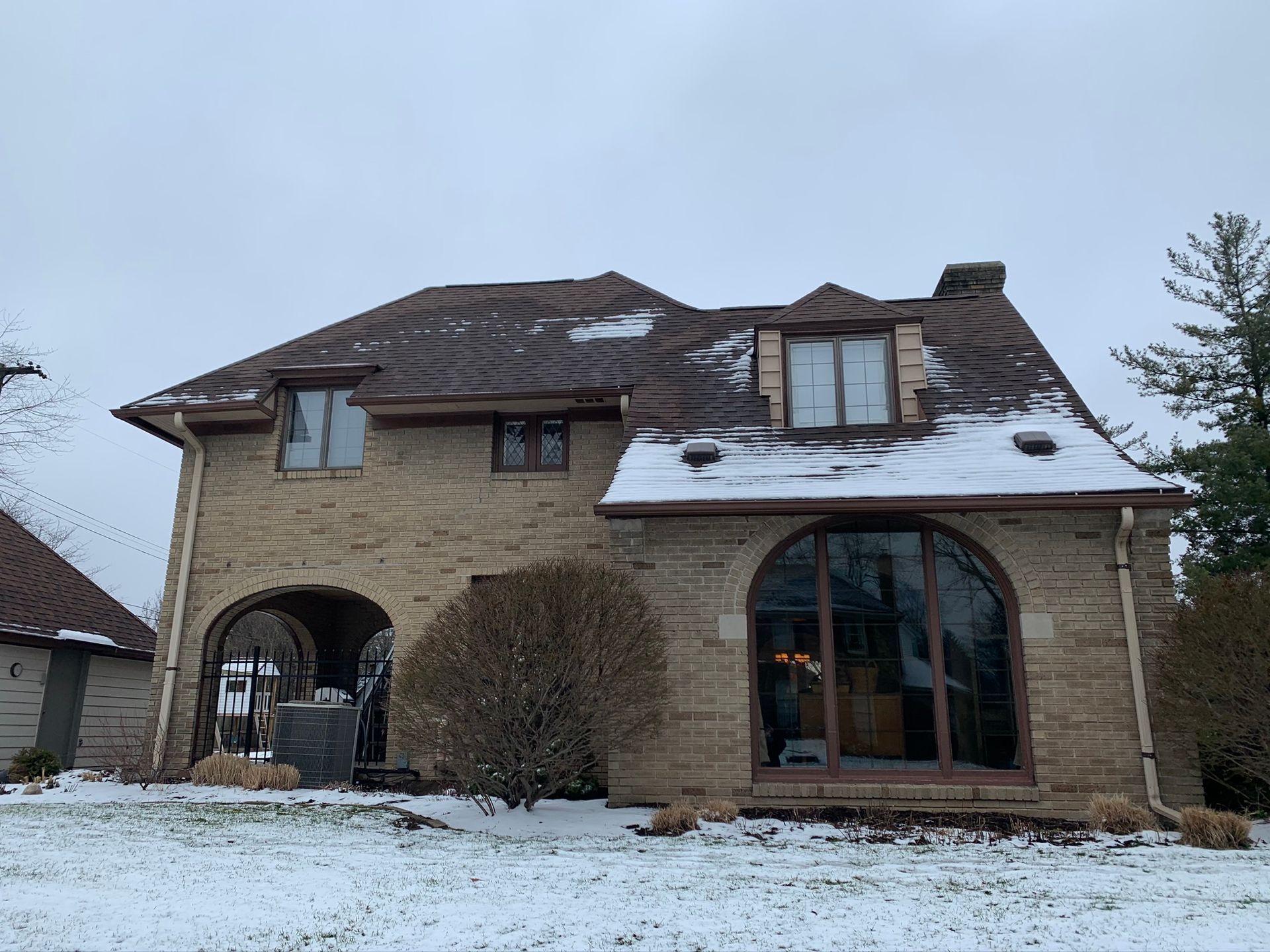 Snow-covered stone house with a damaged roof and large arched windows on a winter day