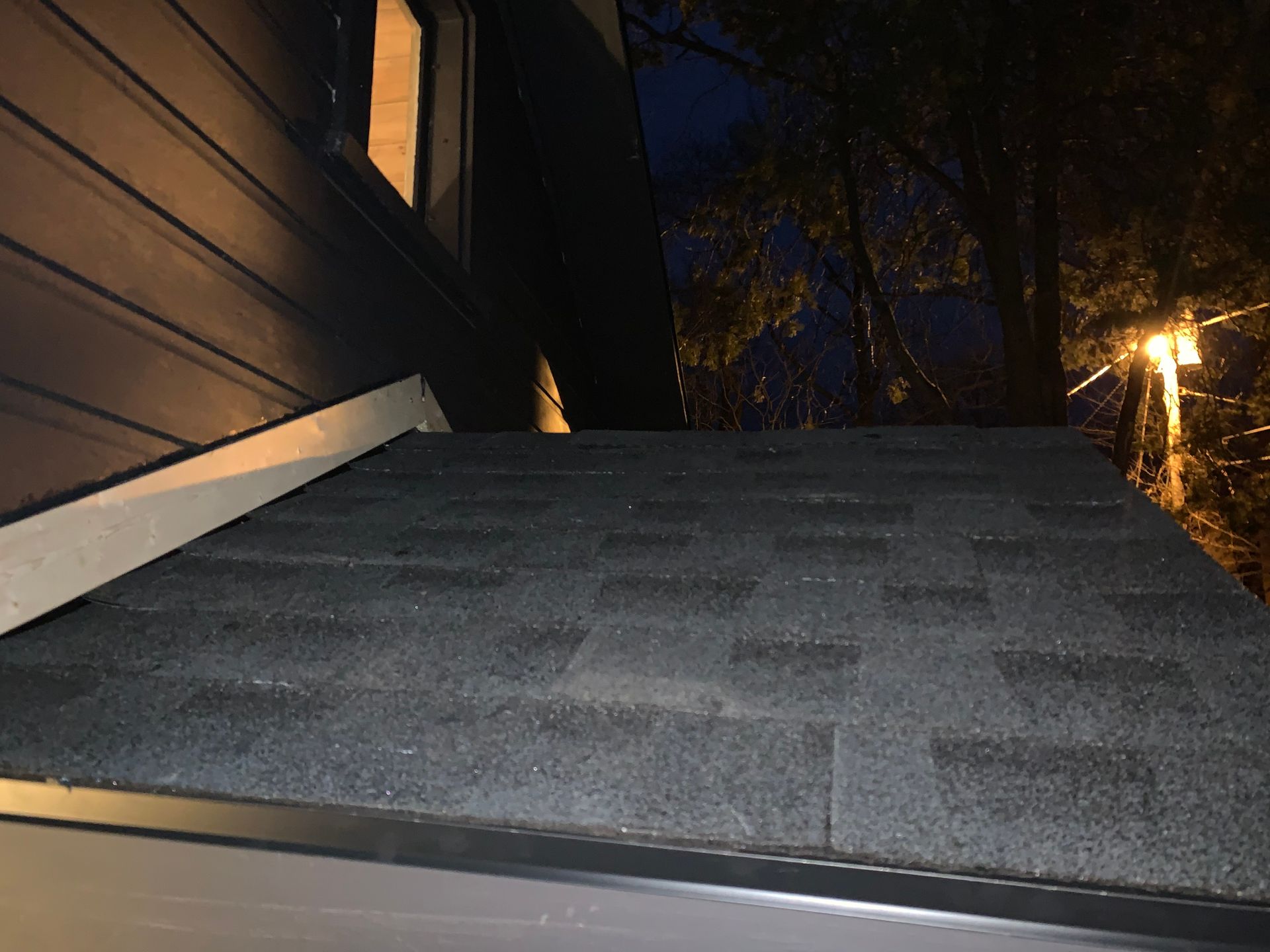 Dimly lit outdoor staircase with gray carpet and a building wall beside it at night