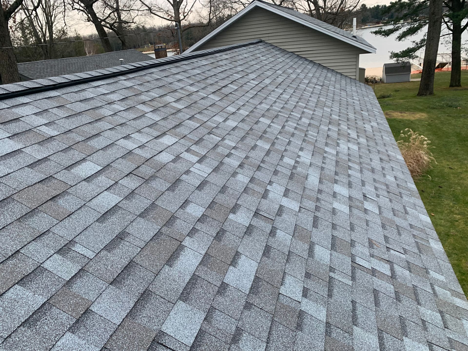 Gray shingled roof with a small dormer, viewed from above on a cloudy day