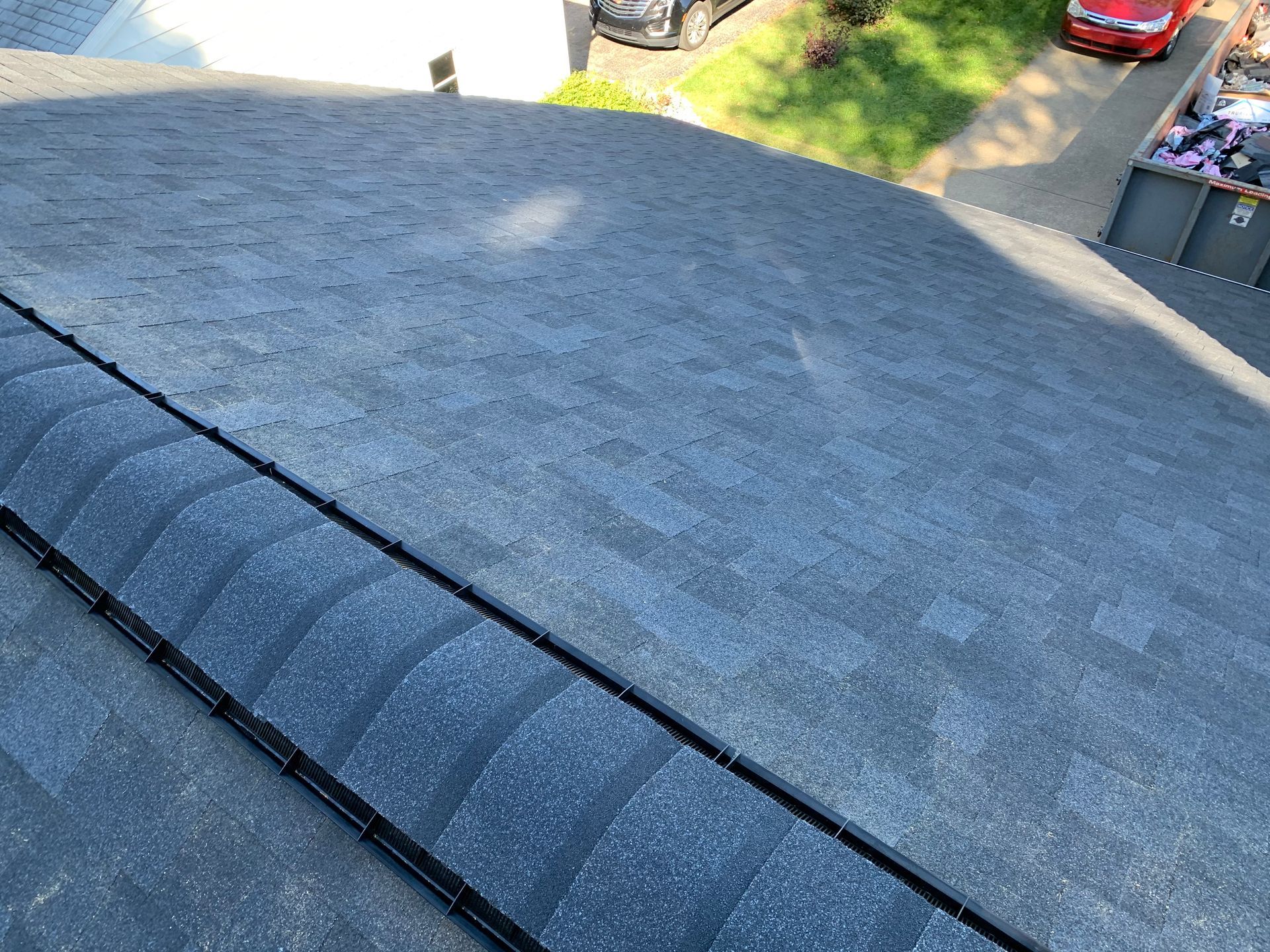 Close-up of a gray shingle roof with a rooftop vent, seen from an upper angle