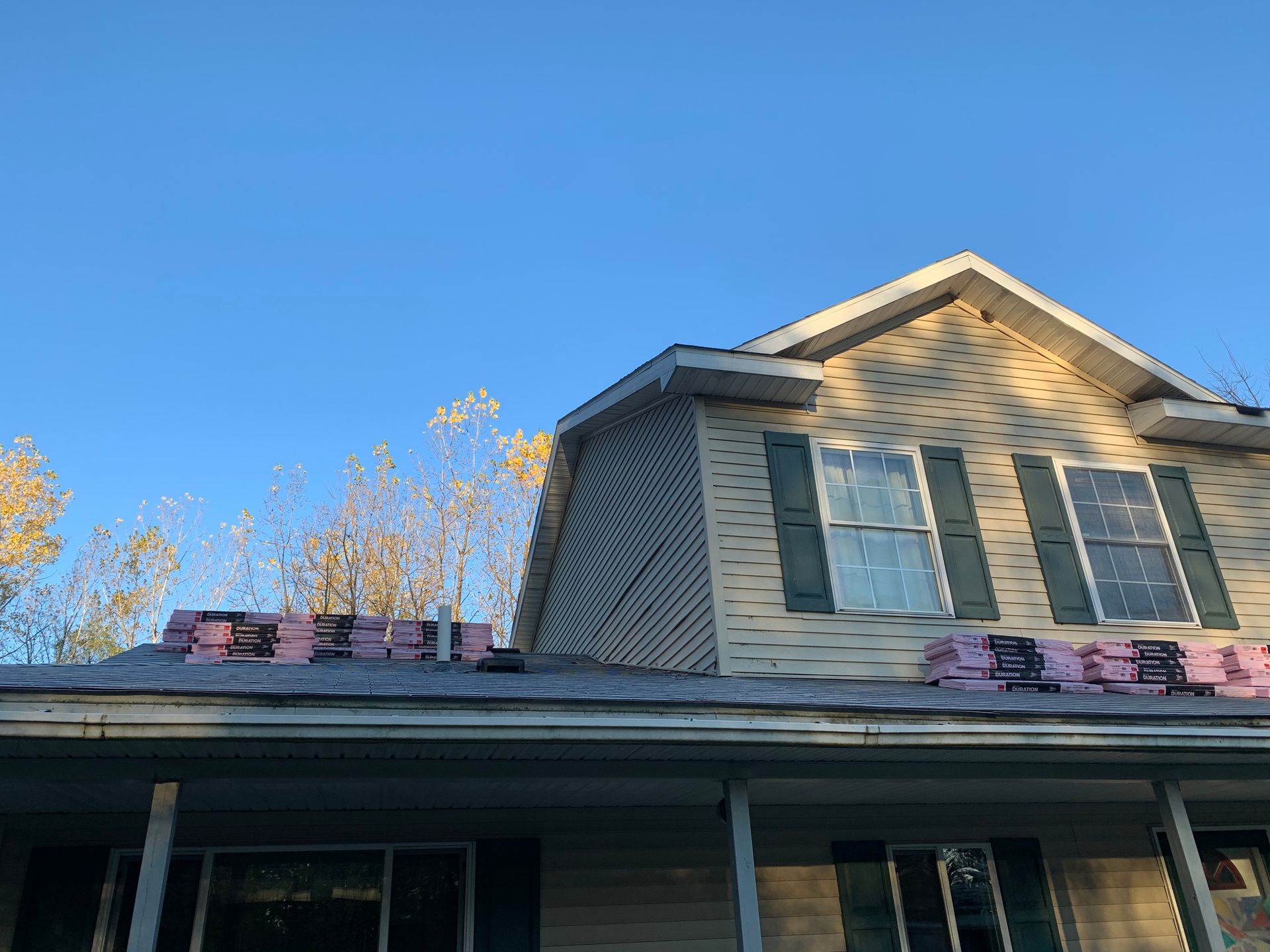 Two-story house with gray siding and shutters under a clear blue sky