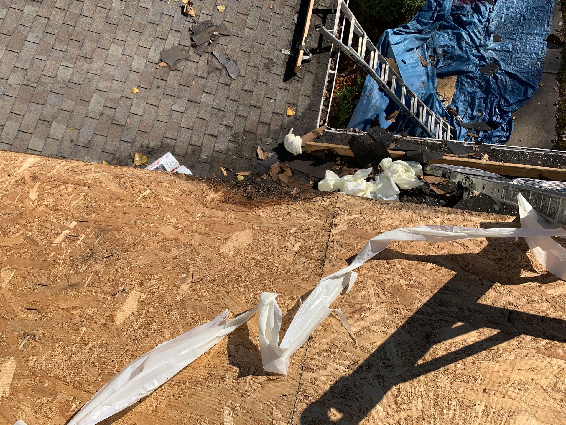 Construction site with exposed dirt slope, brick pavement, and blue tarp-covered debris near wooden framing