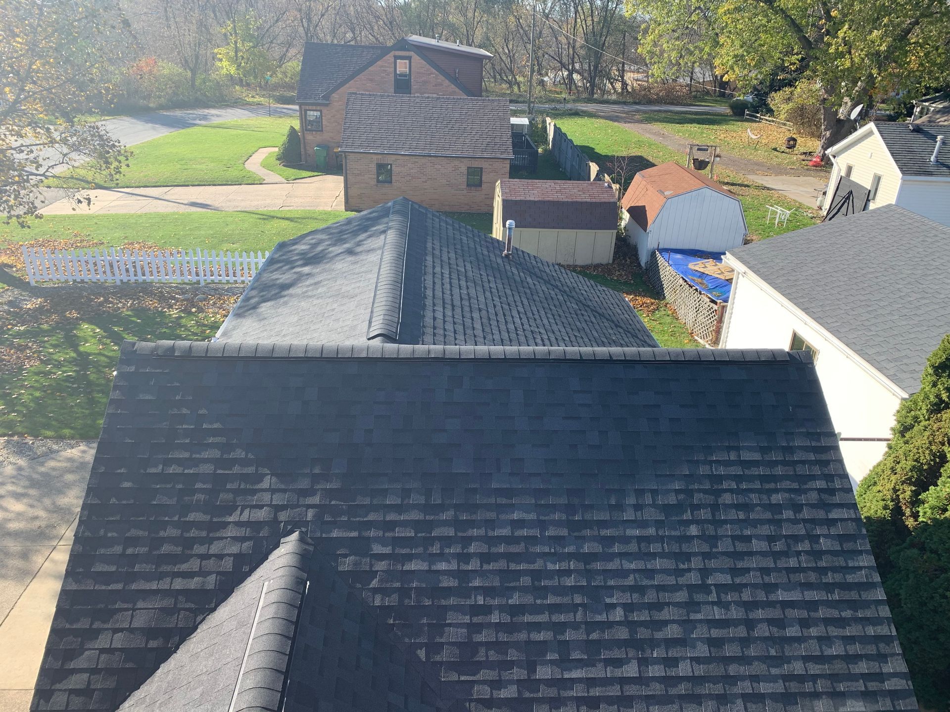 Rooftop view of suburban houses, lawns, and trees on a sunny day
