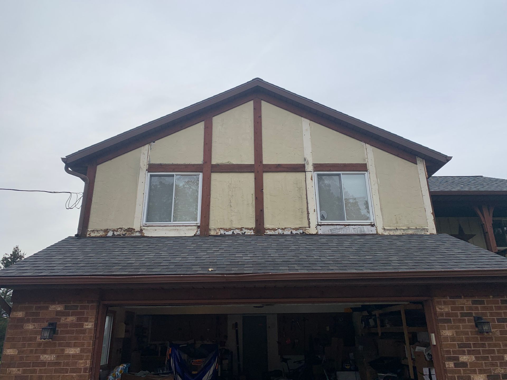 Front view of a two-story house with beige siding, brown trim, and an open garage.
