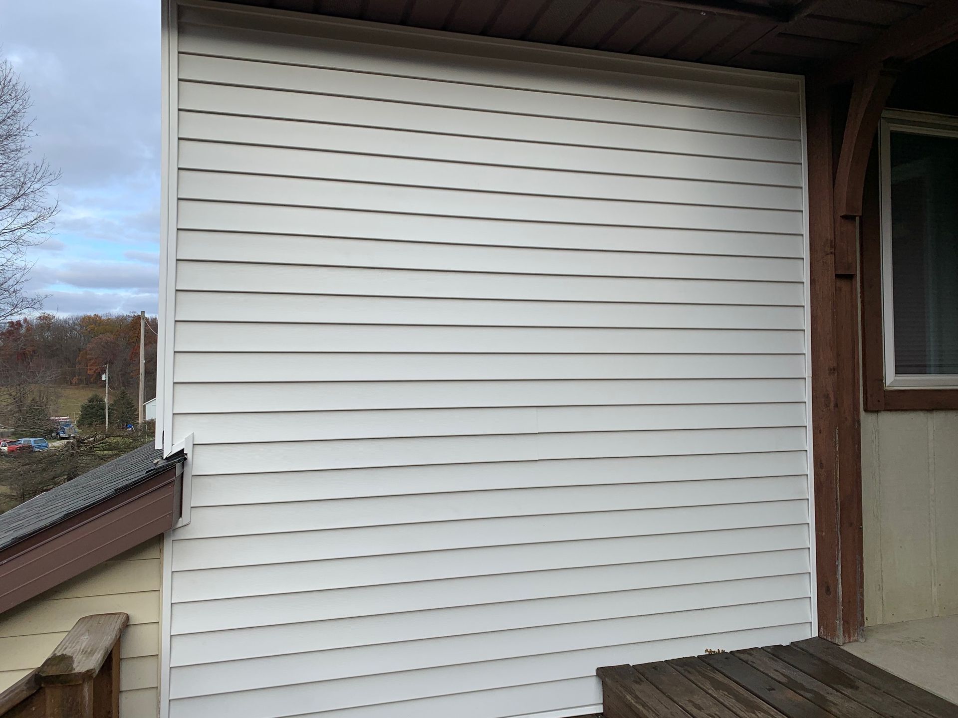 White vinyl siding on a house exterior beside a porch and window