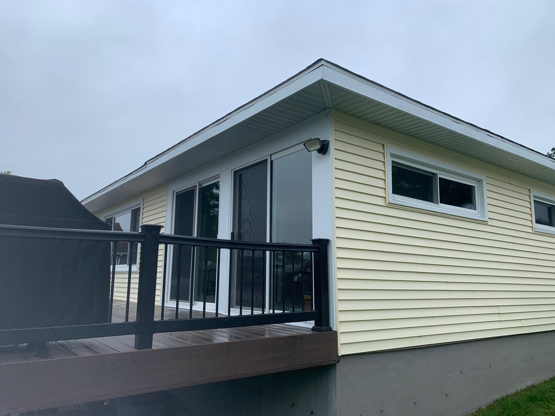Modern house exterior with white siding, black deck railing, and sliding glass doors
