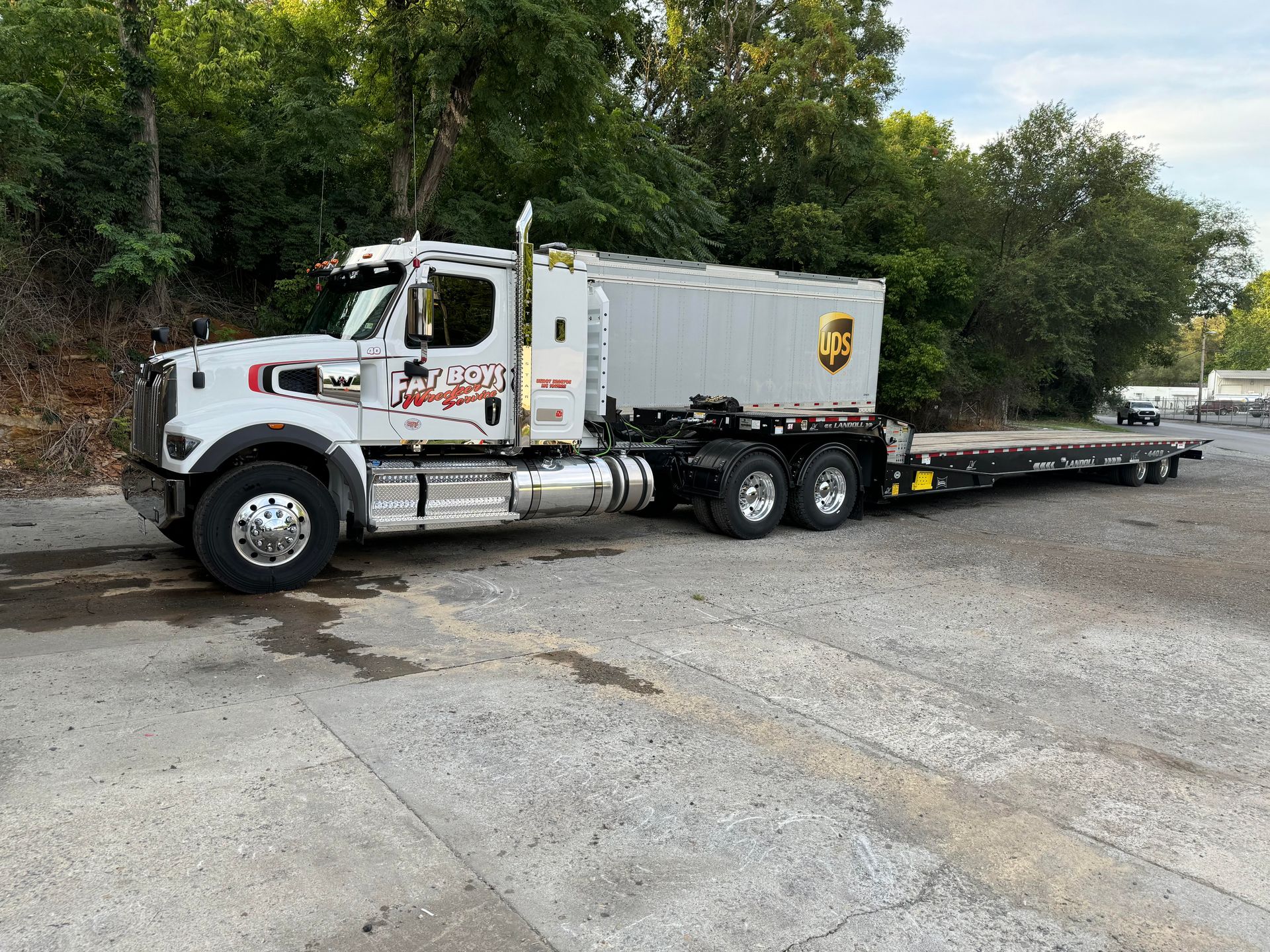 A semi truck with a trailer attached to it is parked in a parking lot.