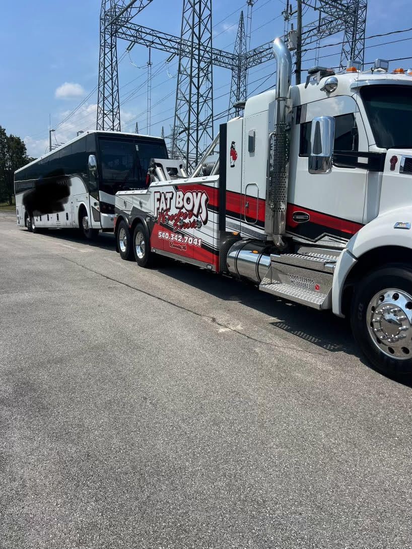 A tow truck is towing a bus down a road.