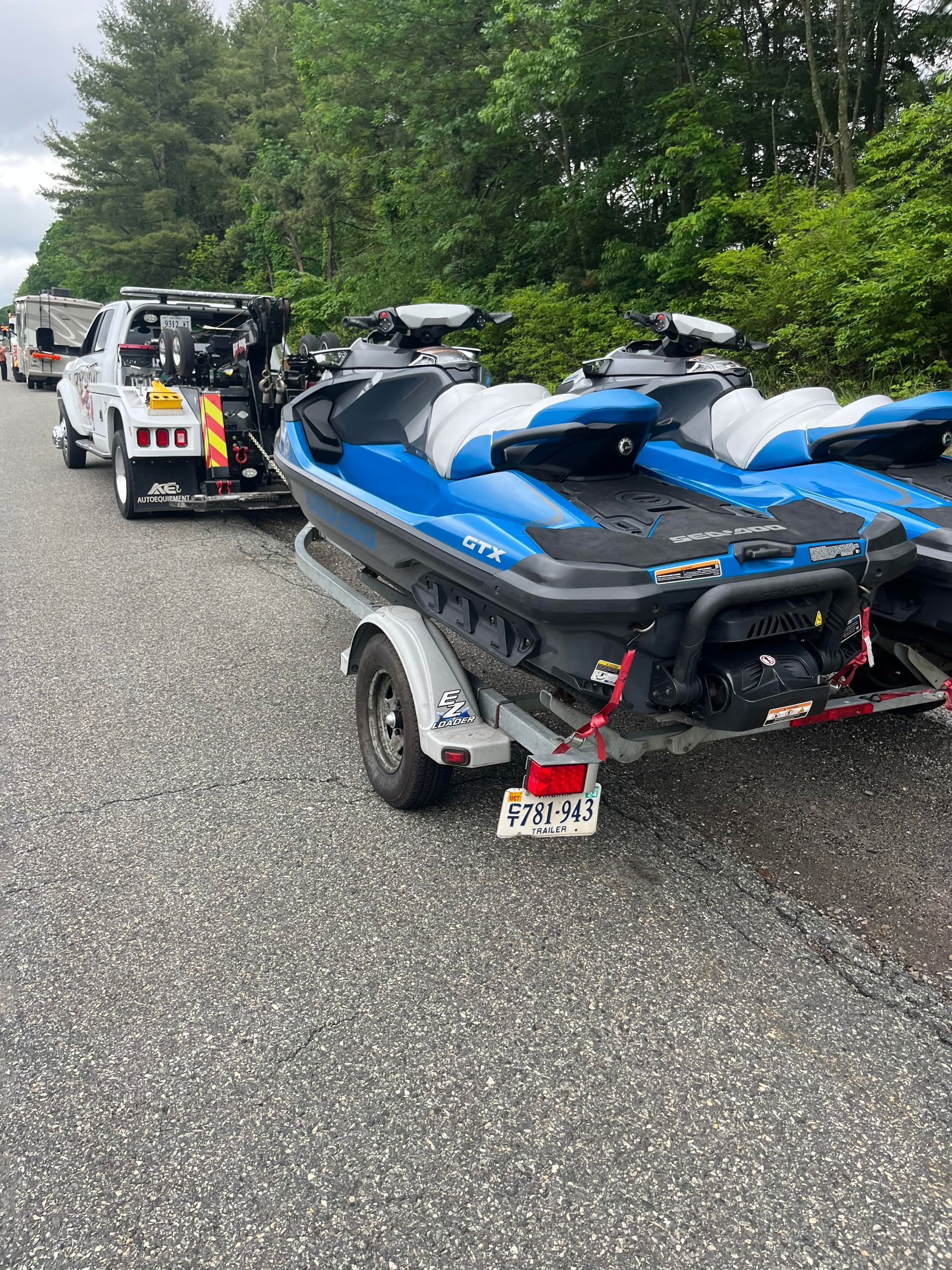 A tow truck is towing a jet ski on a trailer.