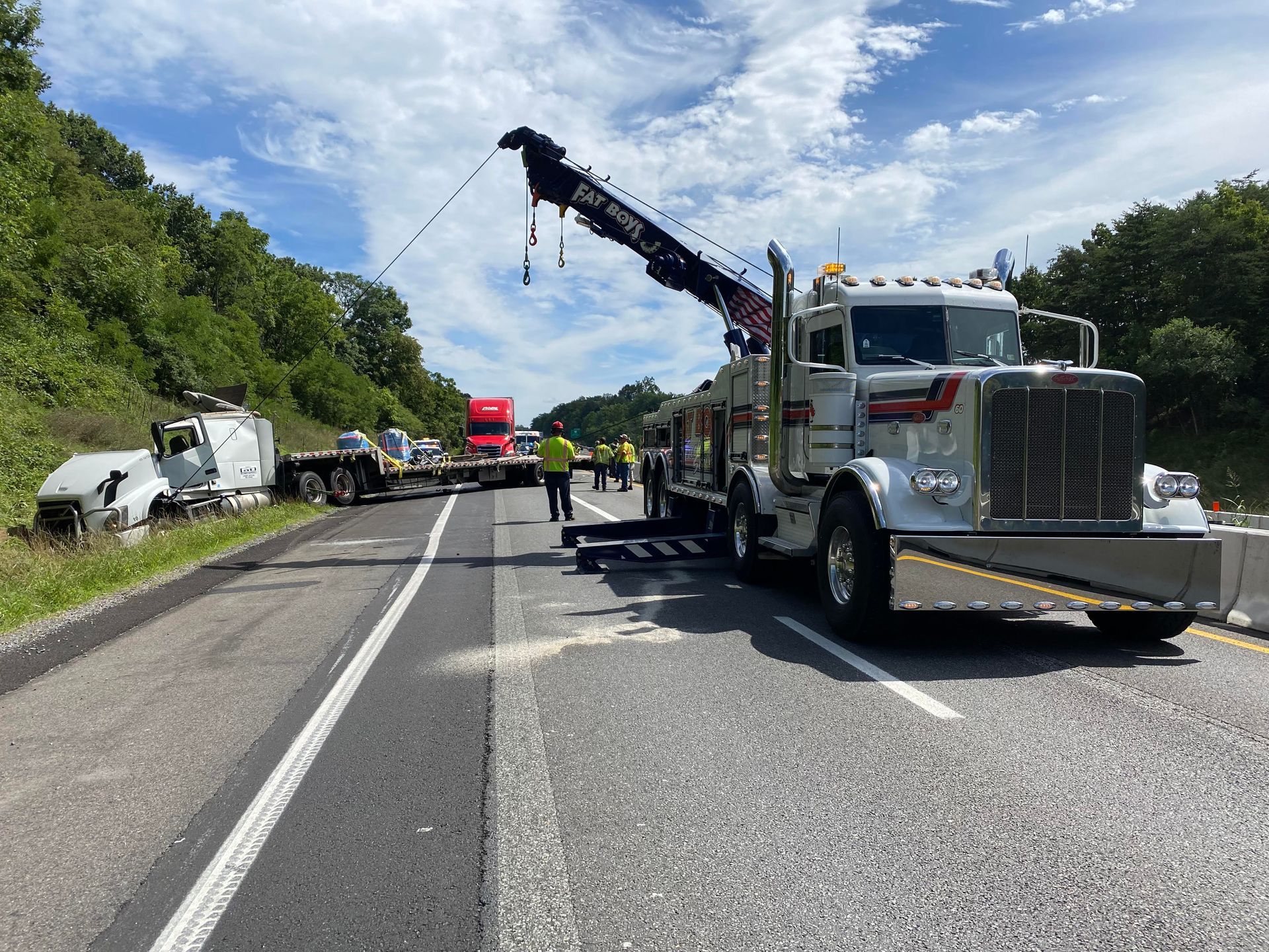 A tow truck is sitting on the side of a highway.