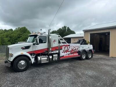 A white and red tow truck is parked in front of a garage.