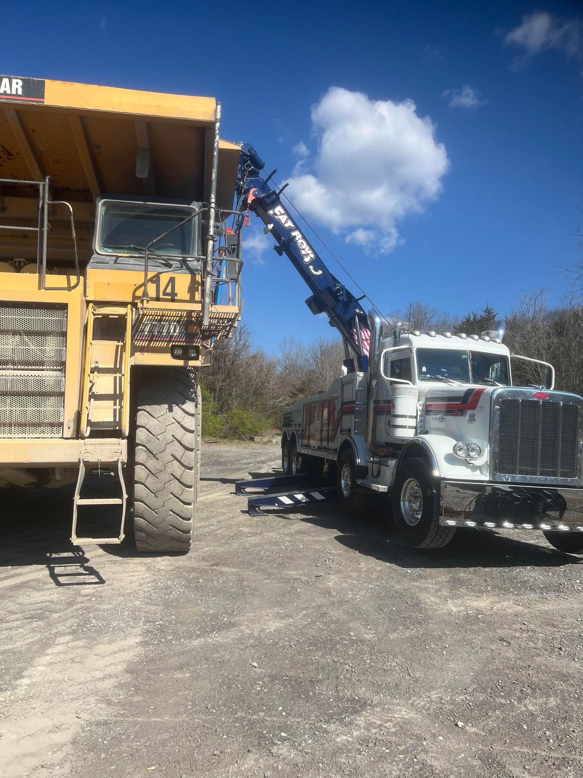 A large yellow dump truck is being towed by a tow truck.