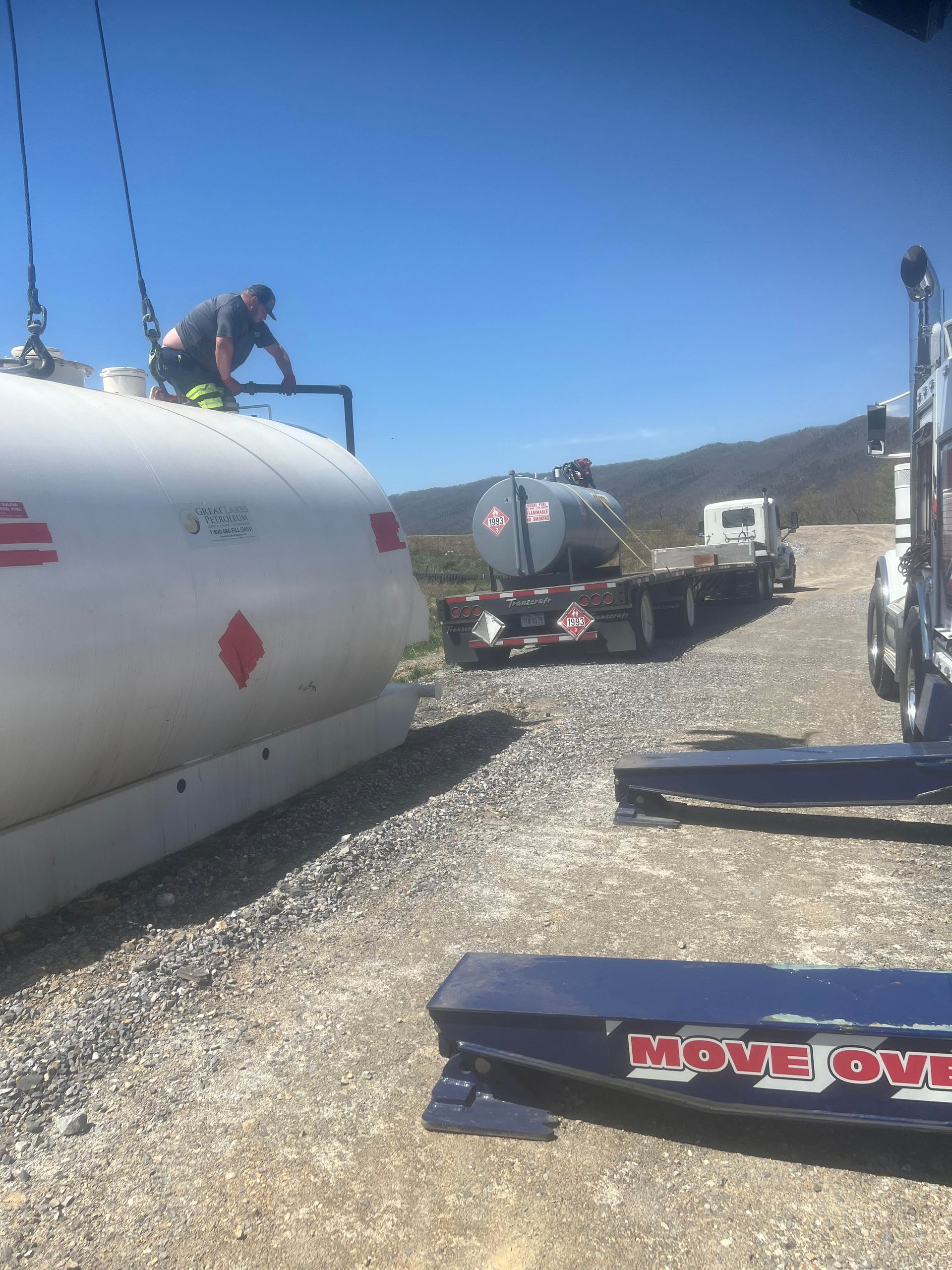 A man is standing on top of a propane tank next to a truck.