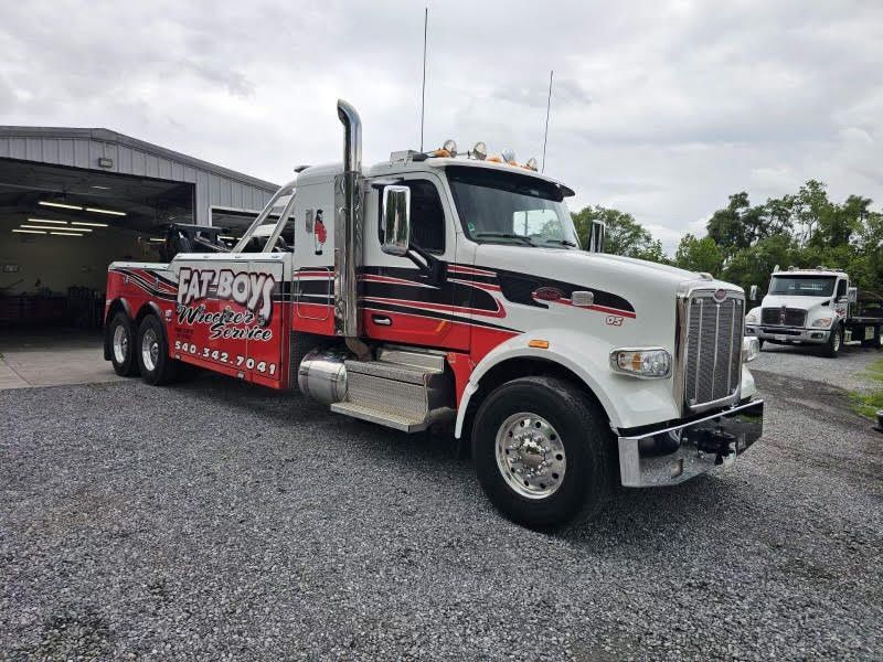 A white and red tow truck is parked in a gravel lot.