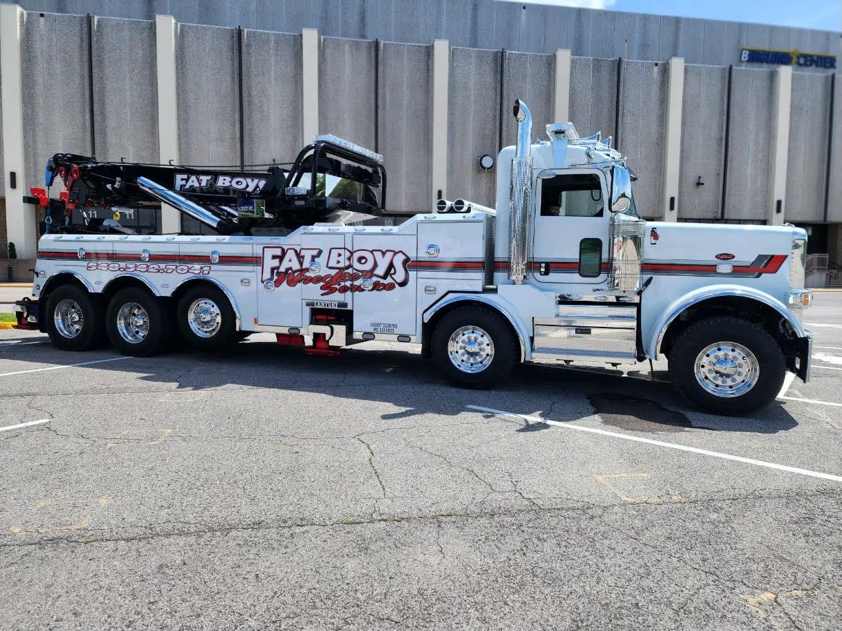 A white tow truck is parked in a parking lot in front of a building.