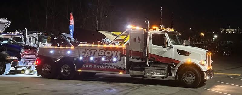 A tow truck is parked in a parking lot at night.