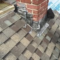 A close-up of a brick chimney showing improperly installed metal step flashing on a sloped shingle roof.