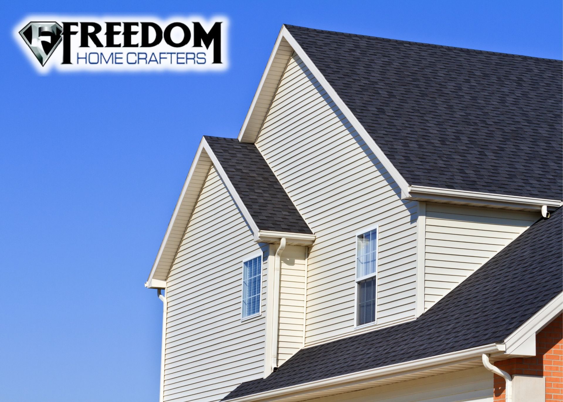 Two-story house with gray roof, cream siding, and blue sky, Freedom Homecrafters logo.