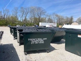 A row of dumpsters are lined up in a parking lot