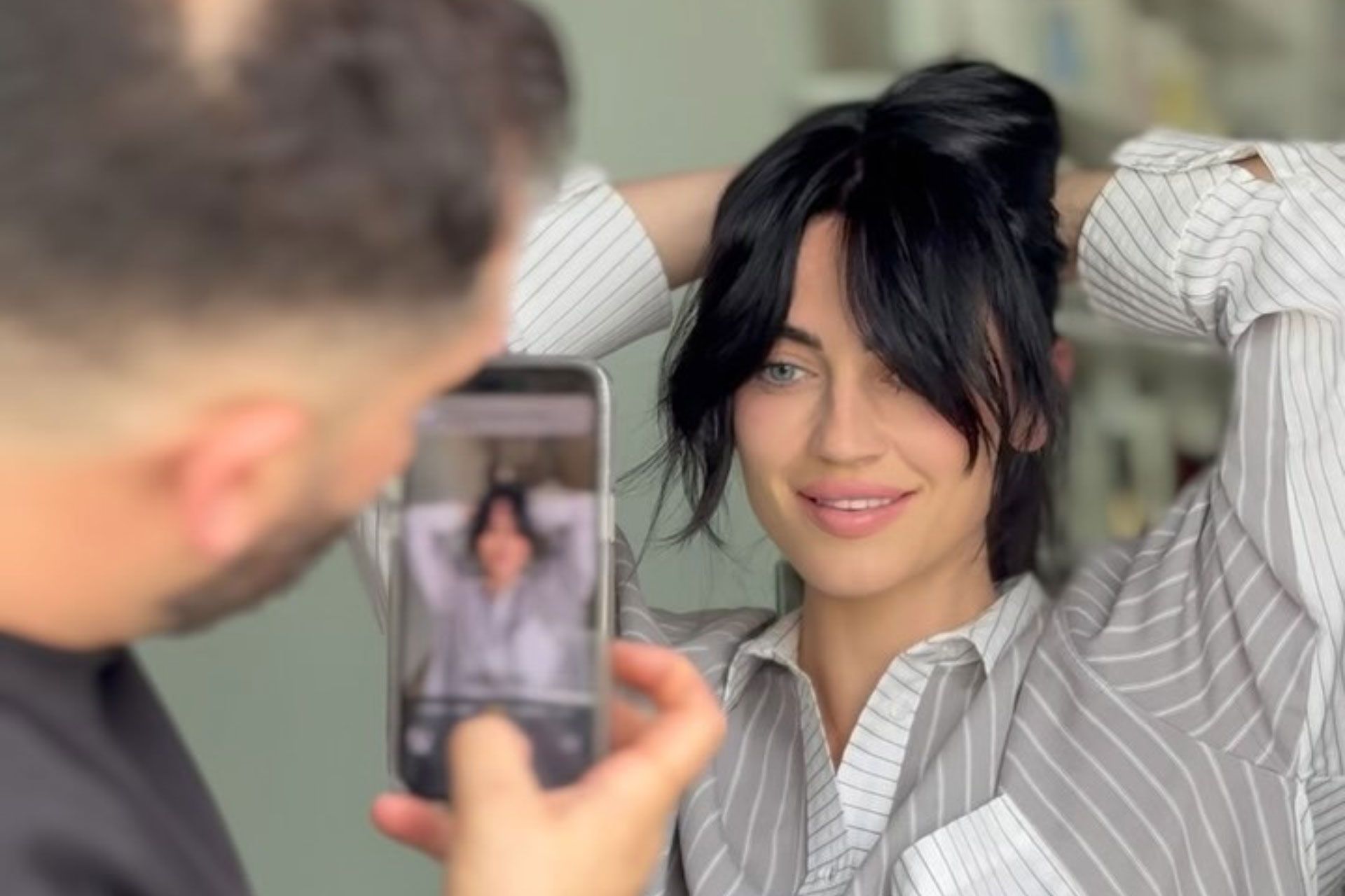 A woman is getting her hair cut by a hairdresser in a salon.