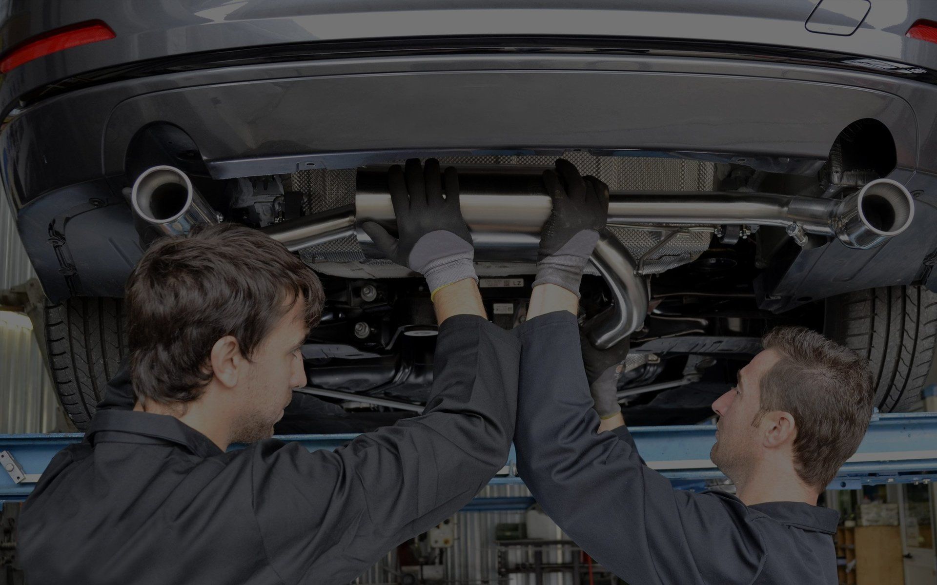 Mechanics installing exhaust components on a hoisted car at Sacco's Auto Repair