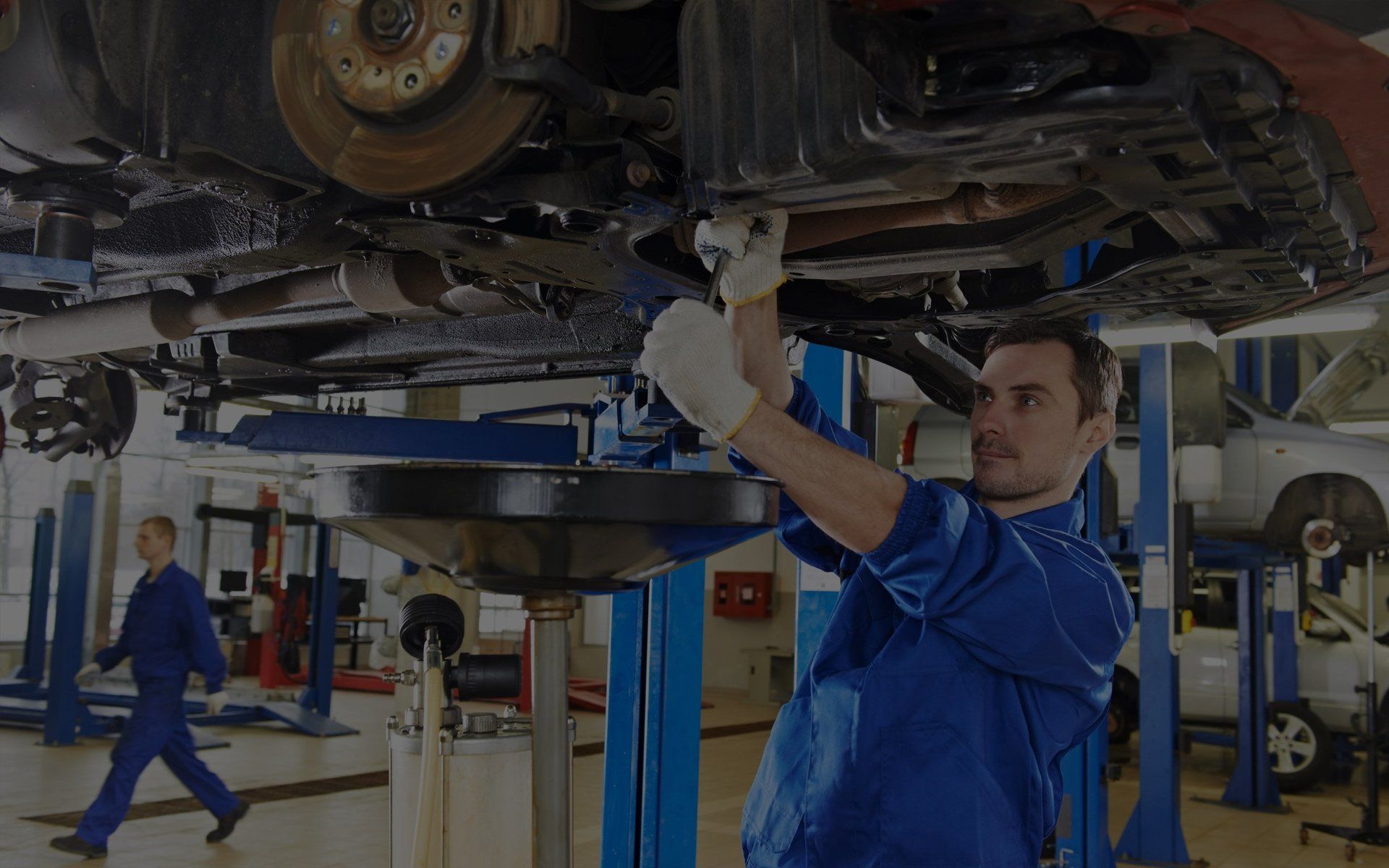 Mechanic performing a tune-up on a hoisted vehicle at Sacco's Auto Repair