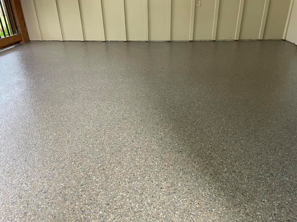 Garage interior with a gray speckled epoxy floor; tools are mounted on the walls.