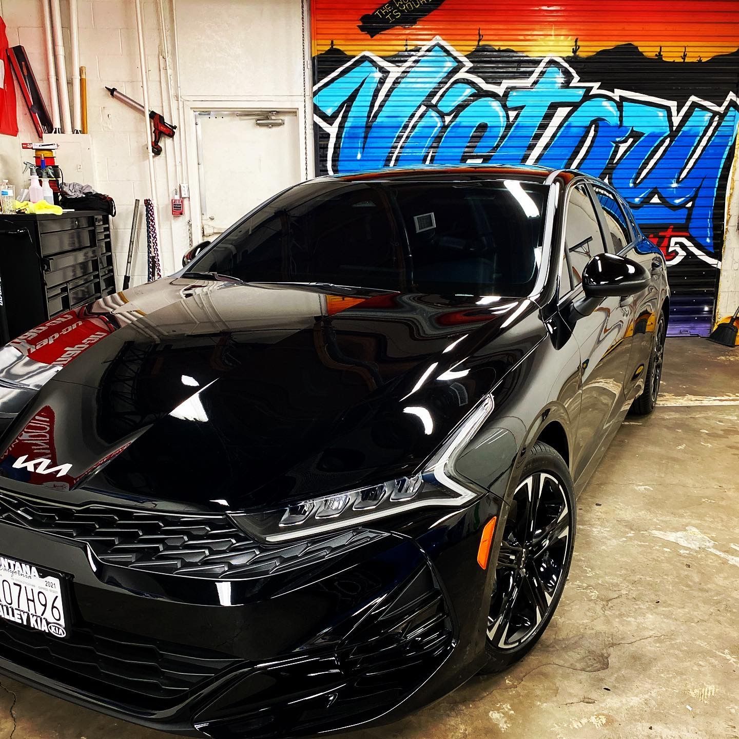Black sports car parked in a garage with colorful graffiti on the wall