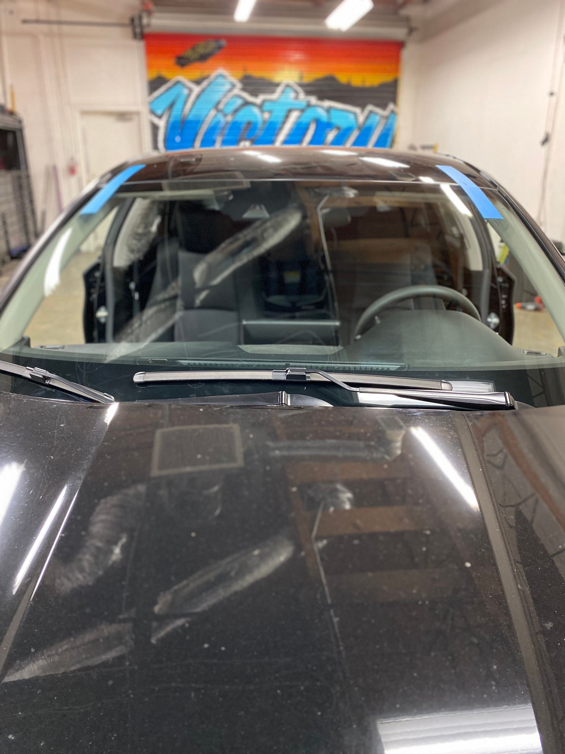 Black car inside a garage with a colorful mural in the background