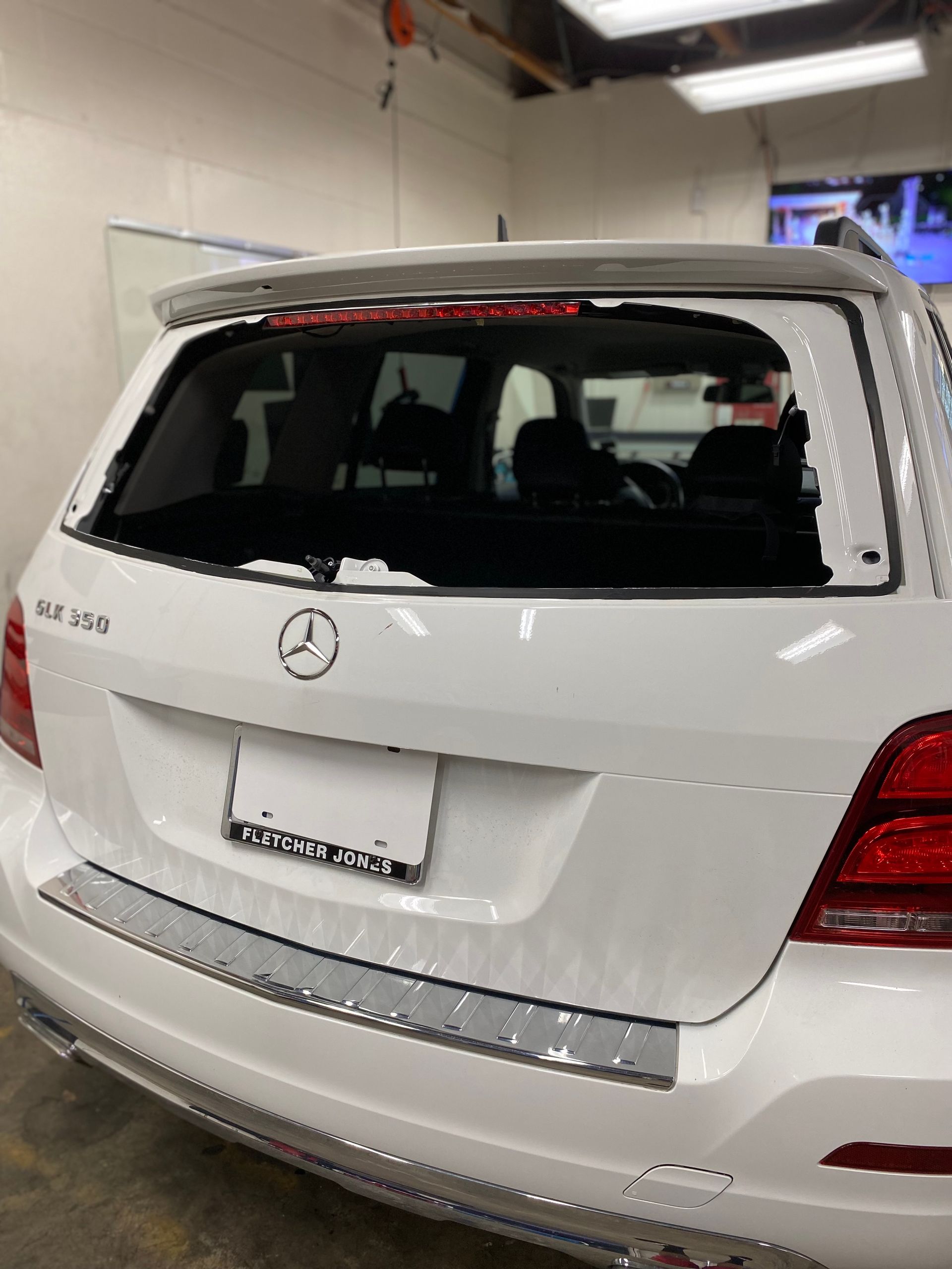 White Mercedes SUV rear with broken back window in a garage, showing rear emblem and license plate area