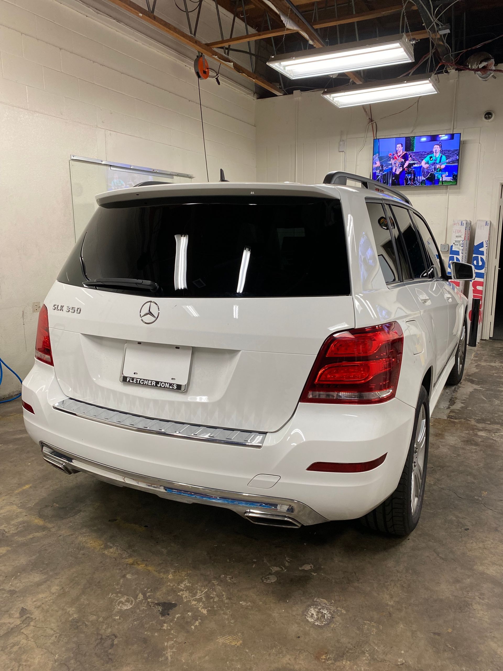 White Mercedes SUV parked in an indoor garage, rear view.
