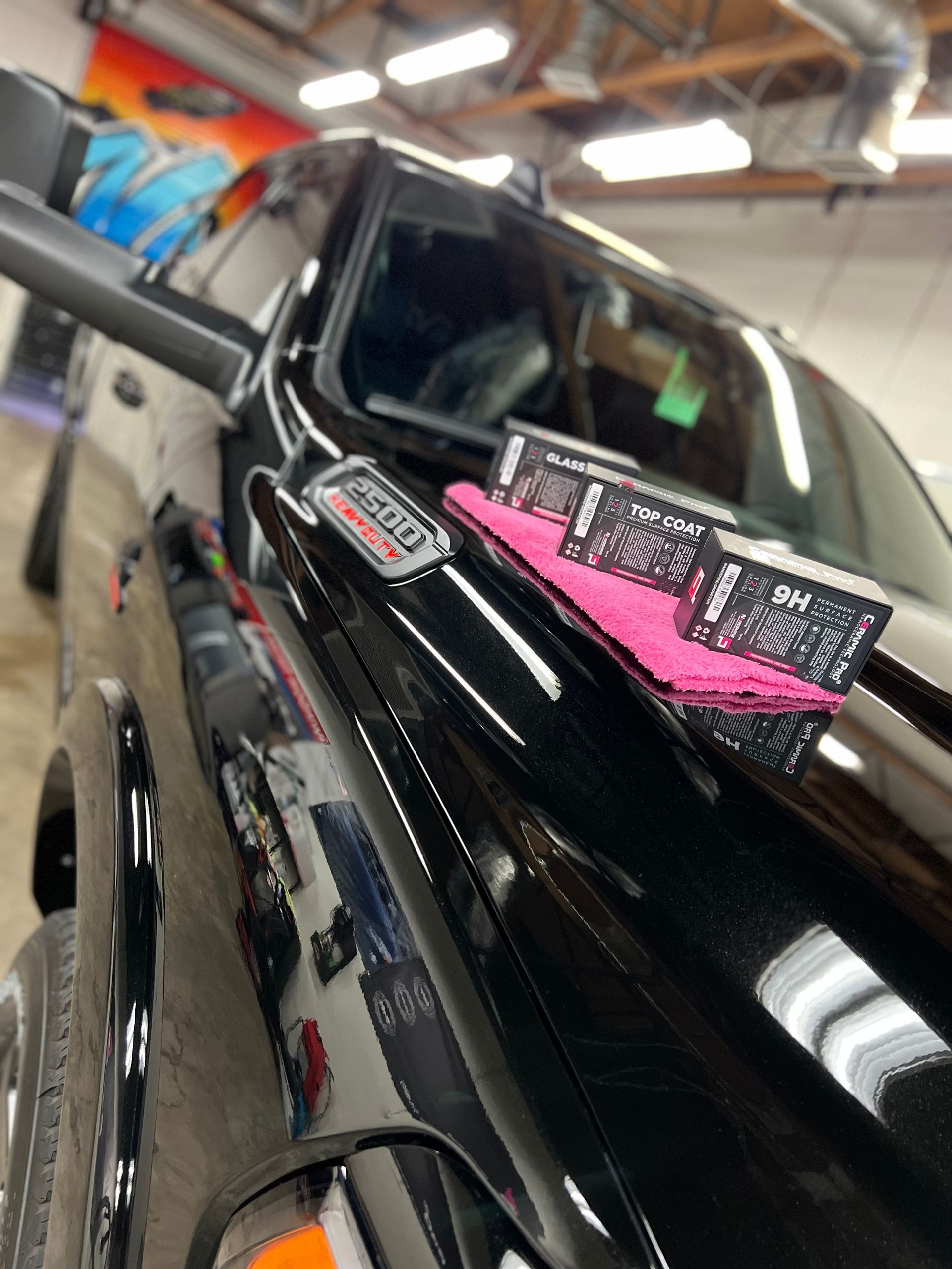 Black pickup truck in a garage with a pink dashboard display and pink cloth on the hood