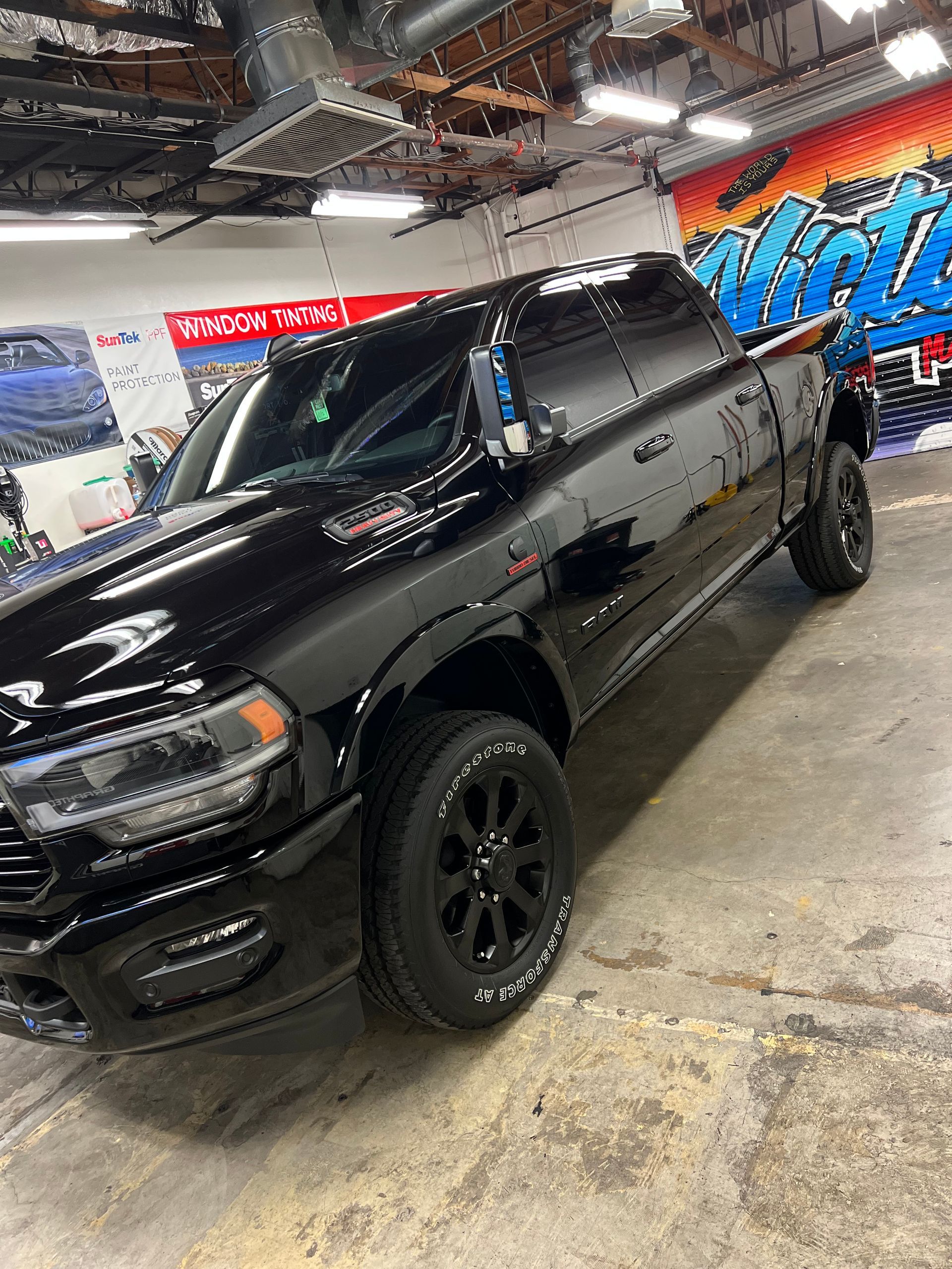 Black lifted pickup truck in a garage, angled view with glossy finish and black wheels