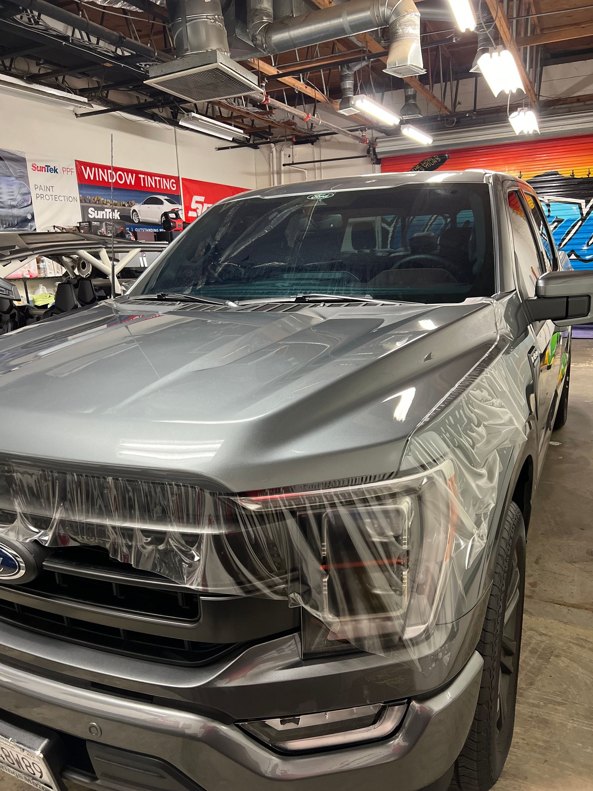 Silver pickup truck in a showroom, front view under bright lights