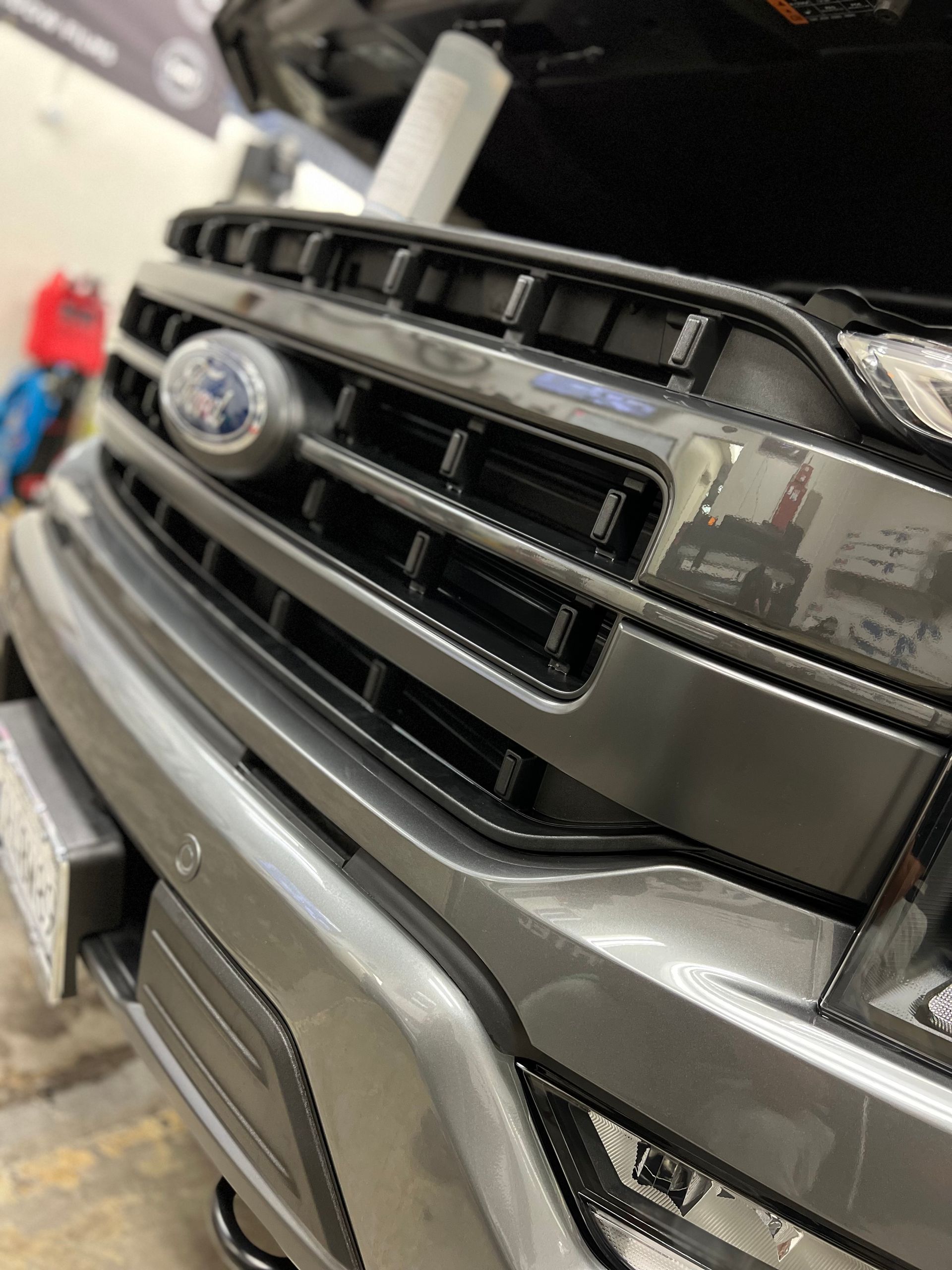 Close-up of a gray Subaru SUV front grille and bumper in a garage