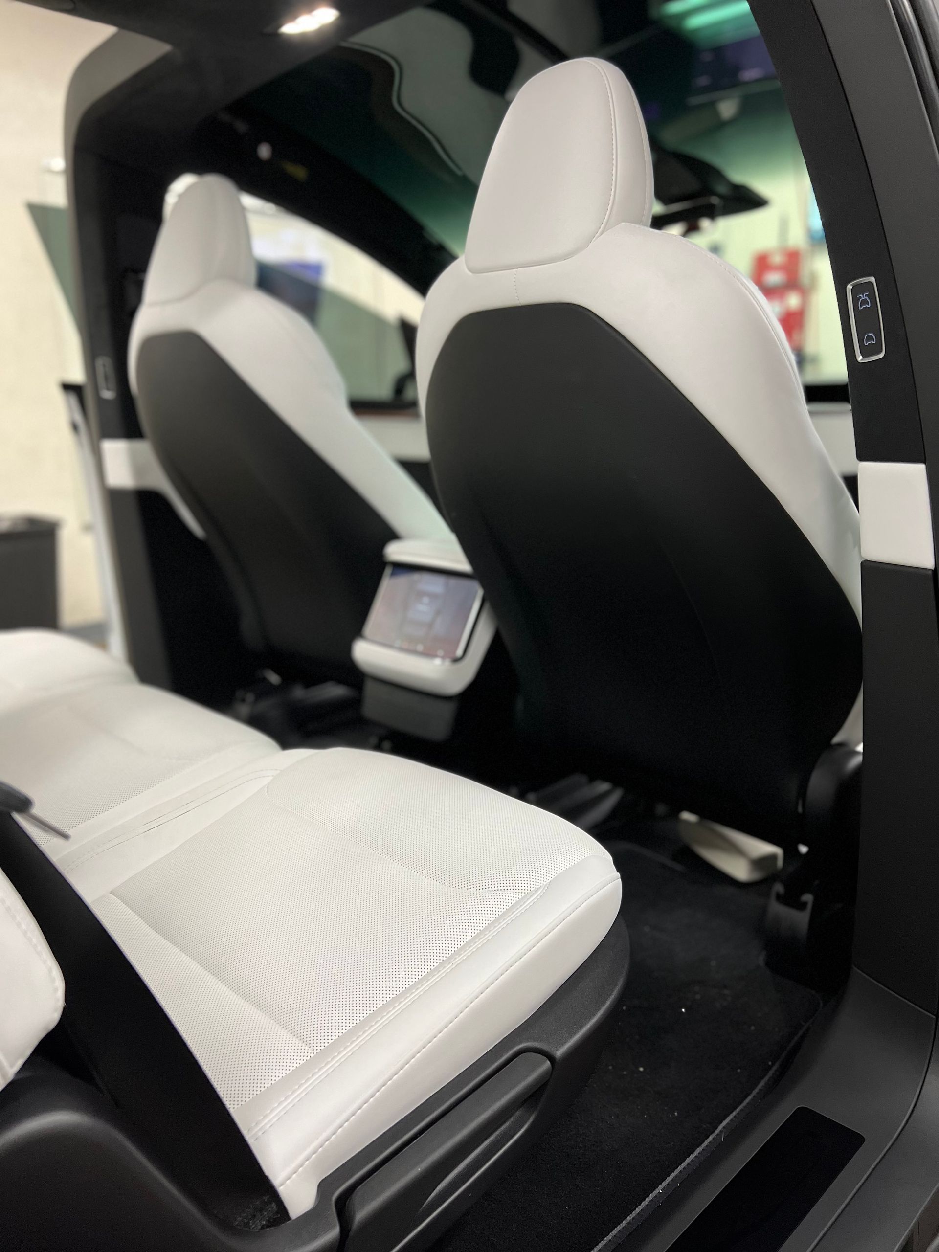 Interior of a modern electric car with white seats and a rear center touchscreen display