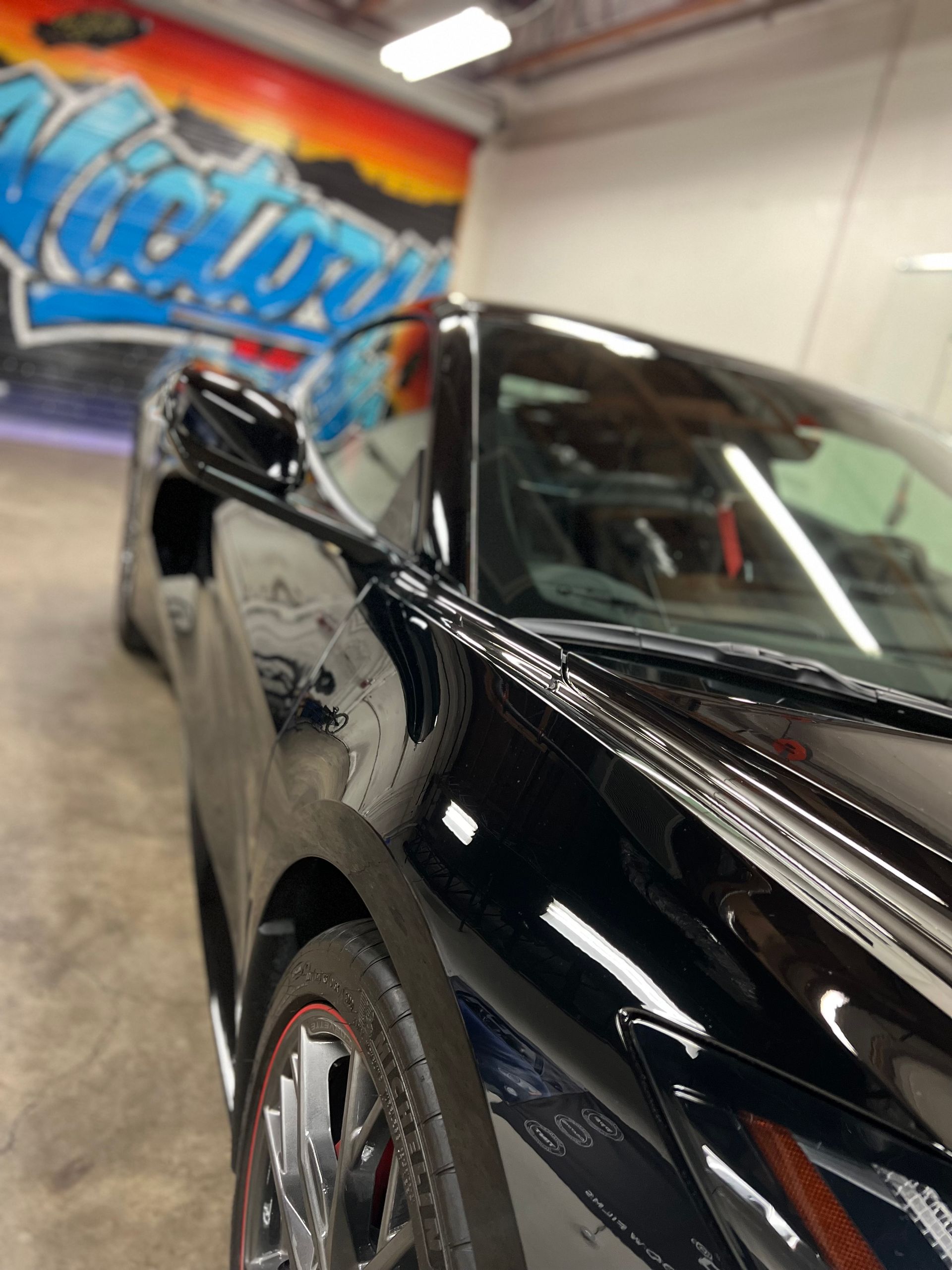 Black sports car in a graffiti-covered garage, close-up on the front side.