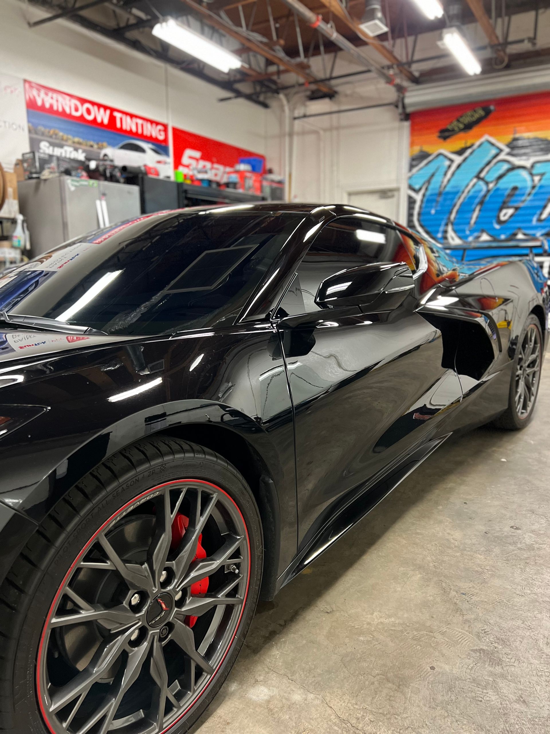 Black sports car with red accents in an auto shop garage