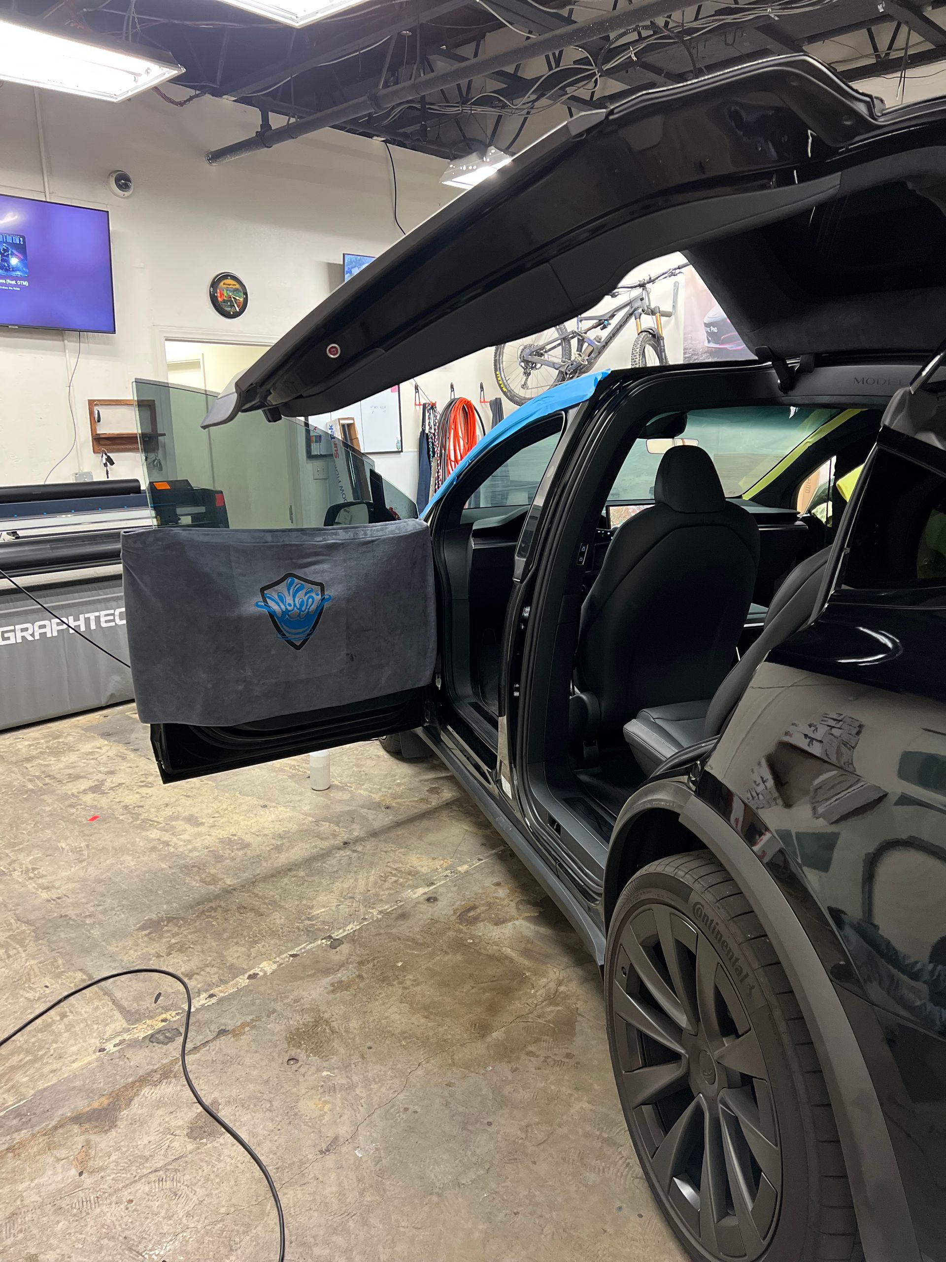 Black SUV with gullwing doors open in a garage, showing a black interior.