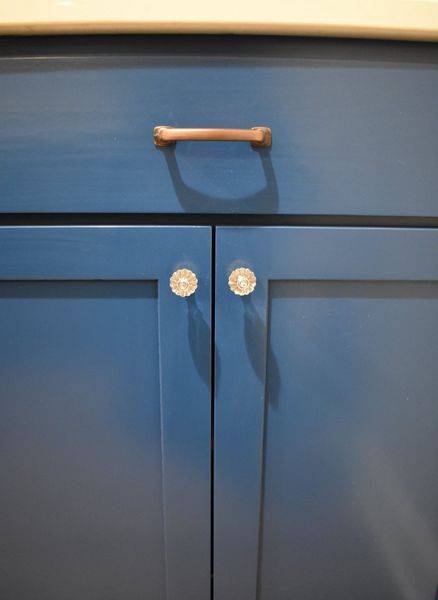 Blue cabinet doors with a wooden handle and crystal knobs.