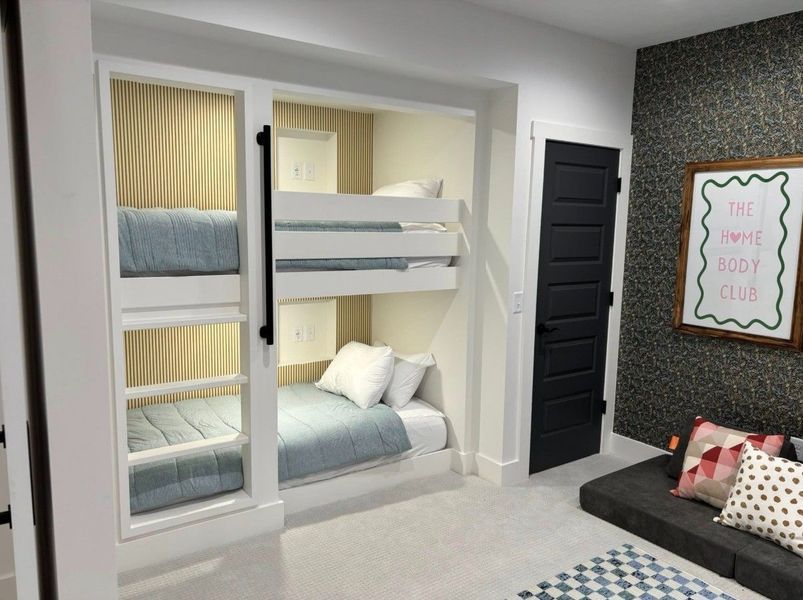 Built-in bunk beds with two levels and an adjacent single bed, in a modern bedroom with gray walls and a black door.