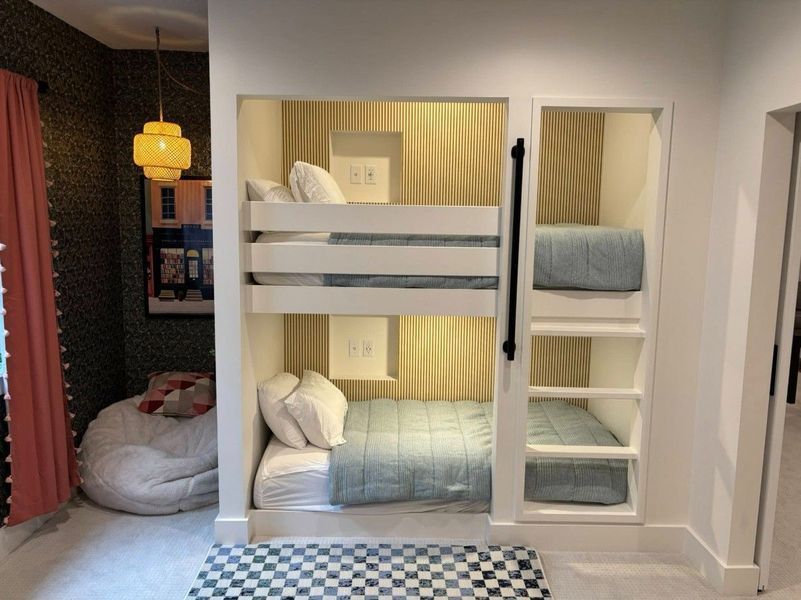 Built-in bunk beds with white frame, blue bedding, and a gold slat accent wall. Checkerboard rug.