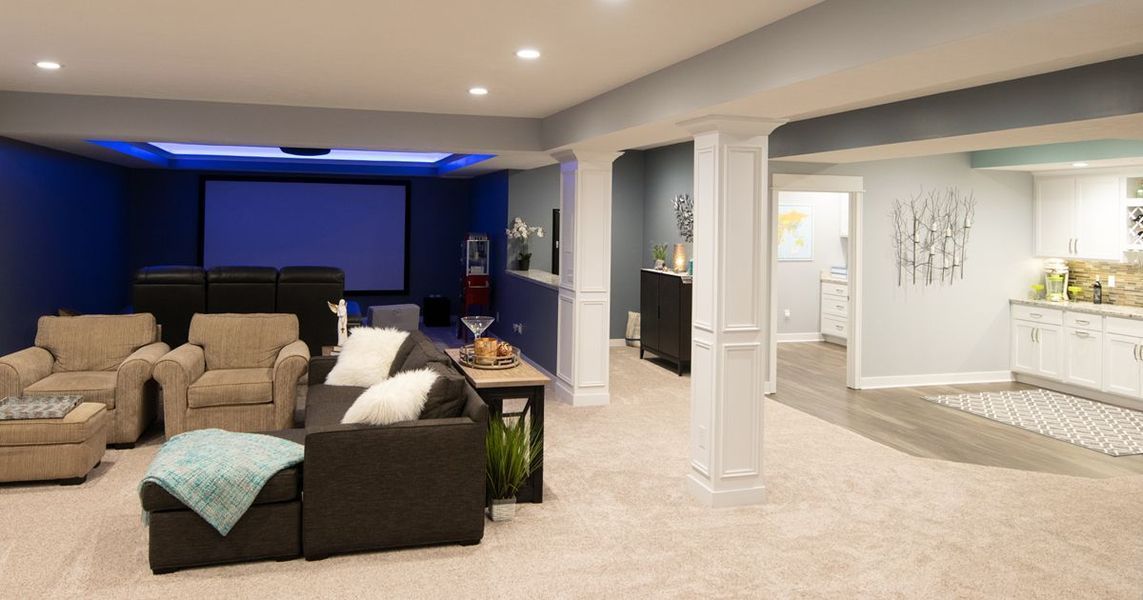 Finished basement with home theater, seating, and a wet bar area; neutral colors.