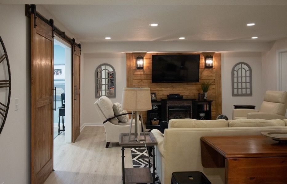 Living room with barn doors, fireplace, TV, and light-colored furniture.