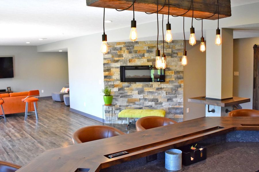 Interior with a stone accent wall, fireplace, and a wooden bar with hanging lights.
