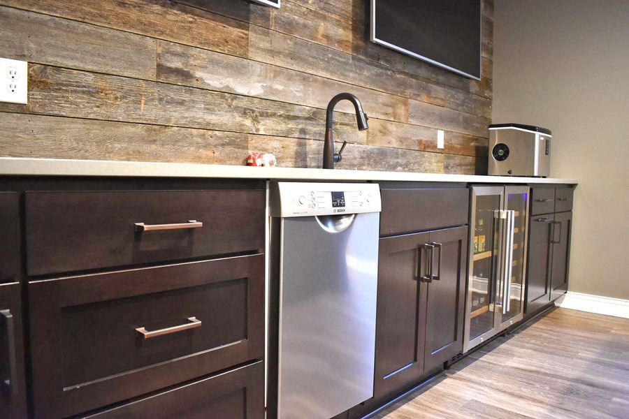 Bar area with wood plank wall, dark cabinets, stainless steel appliances, and faucet.