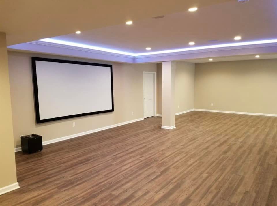 Empty home theater with large projection screen, recessed lighting, and wood-look flooring.