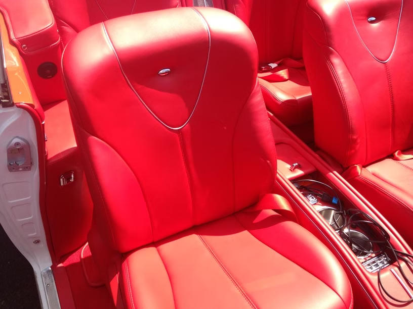 Bright red leather seats inside a vehicle with a center console holding various cables and accessories.