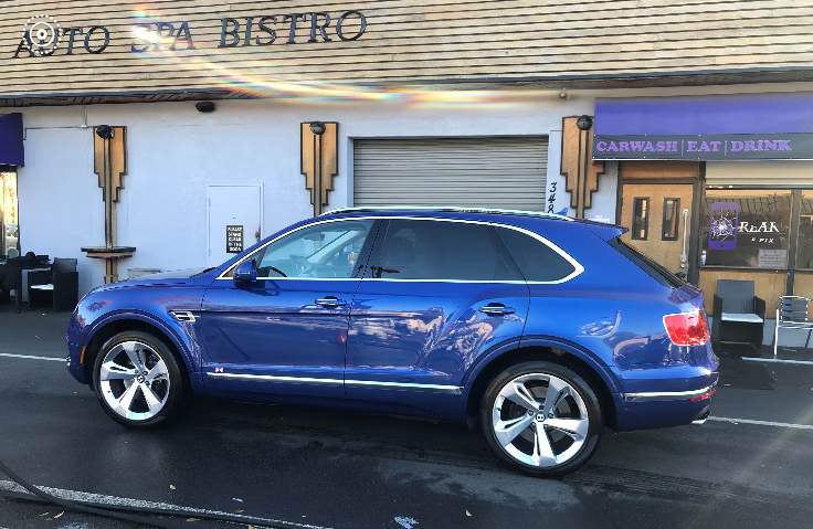 A bright blue SUV parked in front of an Auto Spa Bistro building.